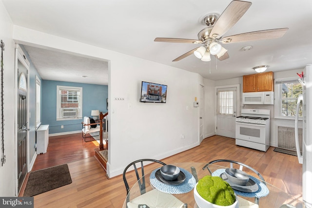 kitchen with ceiling fan, white appliances, radiator heating unit, and light hardwood / wood-style flooring