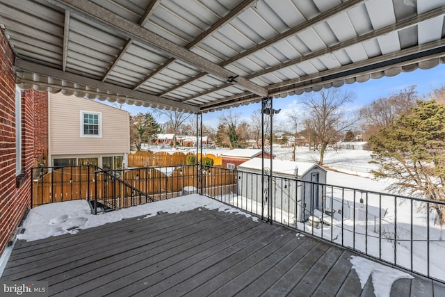 snow covered deck featuring a shed