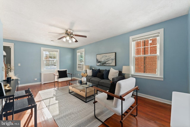 living room featuring radiator, ceiling fan, hardwood / wood-style floors, cooling unit, and a textured ceiling