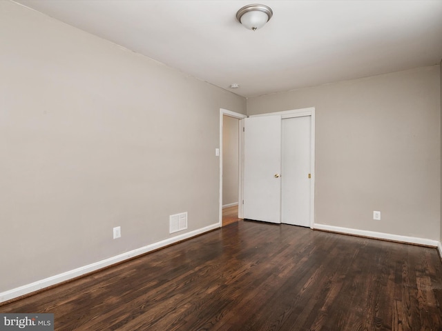 unfurnished bedroom with a closet and dark wood-type flooring