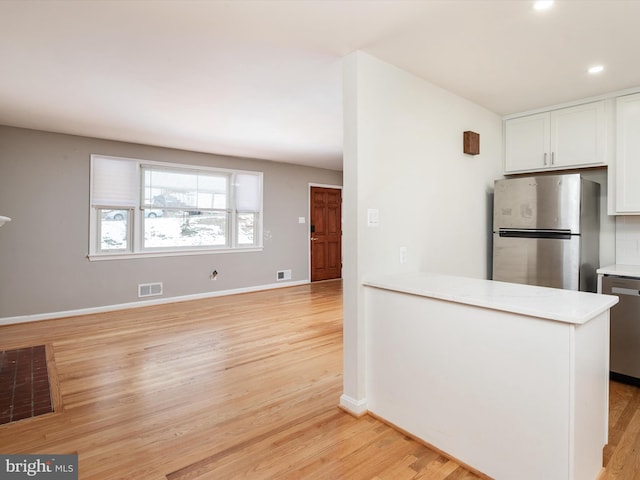 kitchen with white cabinets, stainless steel appliances, and light wood-type flooring