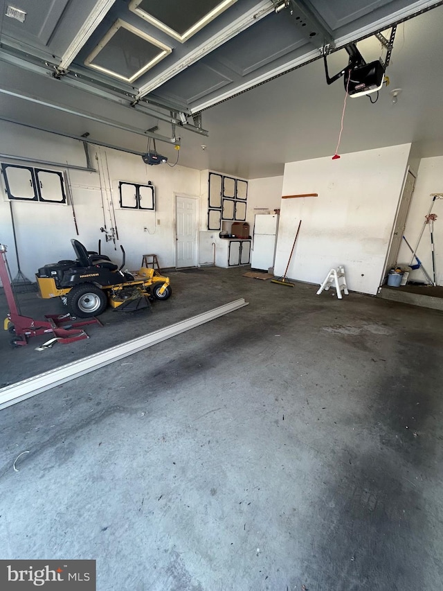 garage featuring white refrigerator and a garage door opener