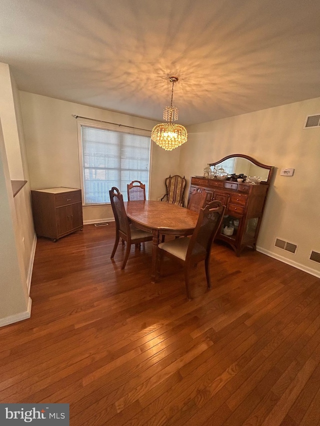 dining area with dark wood-type flooring and an inviting chandelier