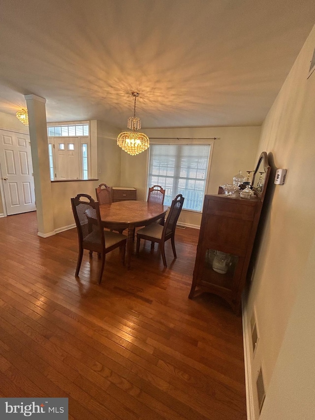 dining area with a notable chandelier and dark hardwood / wood-style flooring