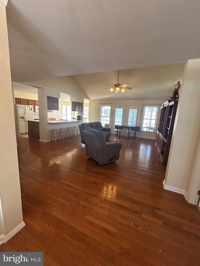 unfurnished living room with ceiling fan, dark wood-type flooring, vaulted ceiling, and sink