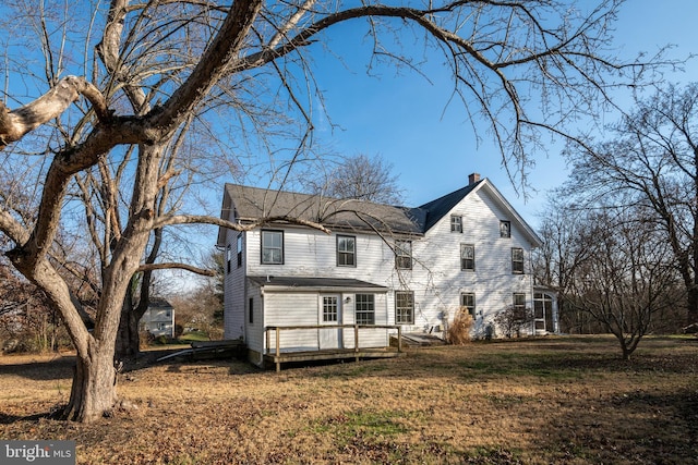 view of front of home with a deck and a front lawn