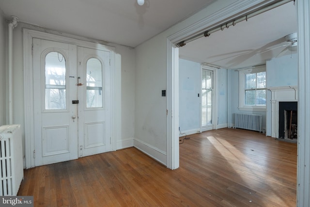 foyer entrance featuring hardwood / wood-style flooring, ceiling fan, and radiator