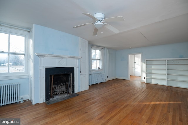 unfurnished living room featuring hardwood / wood-style floors, radiator heating unit, and ceiling fan