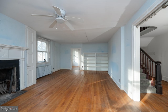 unfurnished living room featuring light hardwood / wood-style flooring, radiator heating unit, and ceiling fan