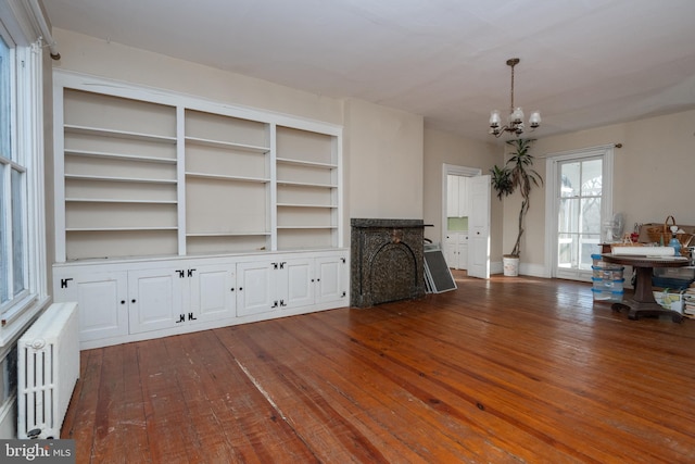 unfurnished living room featuring radiator, a notable chandelier, and dark wood-type flooring