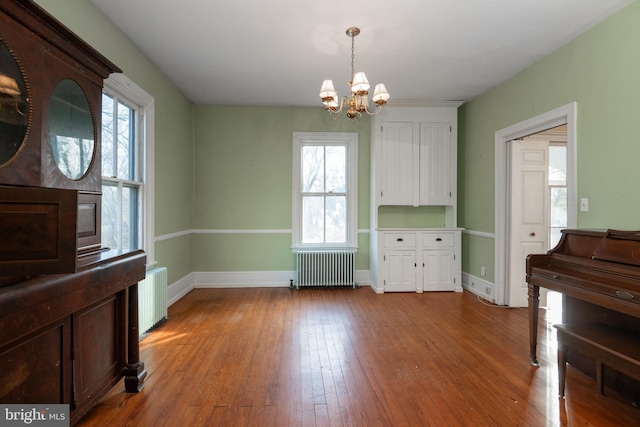 dining space with radiator heating unit, a chandelier, and light wood-type flooring