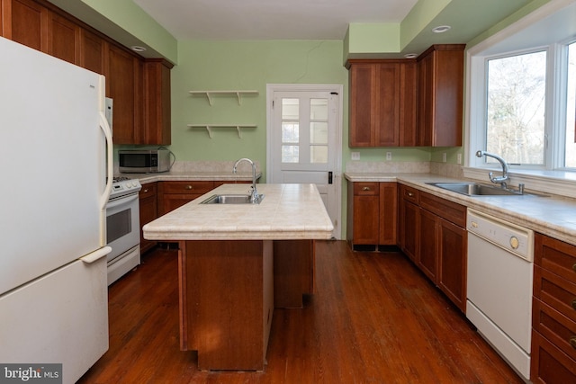 kitchen featuring dark hardwood / wood-style floors, an island with sink, sink, and white appliances