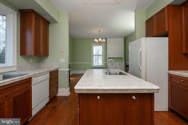 kitchen with a kitchen island with sink, sink, white appliances, and dark wood-type flooring