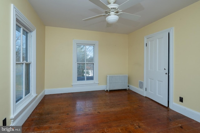 unfurnished room with dark hardwood / wood-style flooring, radiator, and ceiling fan