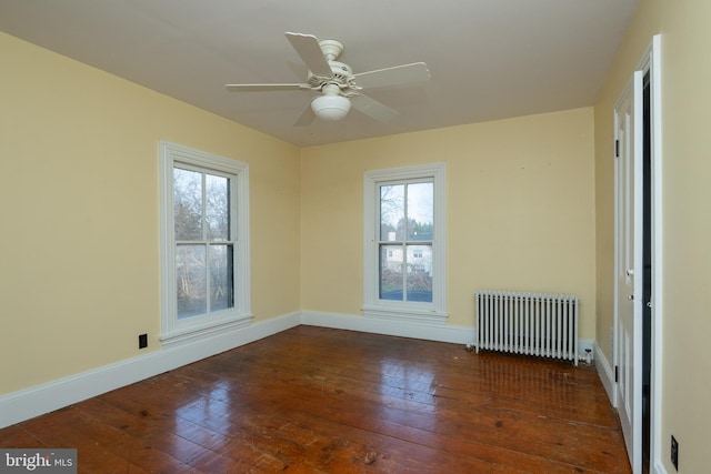 empty room with dark hardwood / wood-style flooring, radiator, plenty of natural light, and ceiling fan