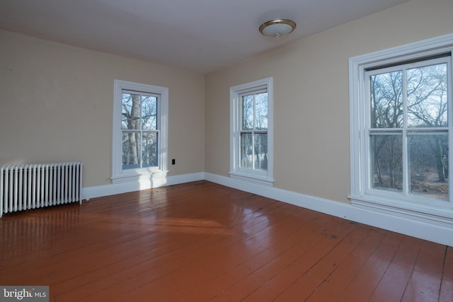 unfurnished room with hardwood / wood-style floors, plenty of natural light, and radiator heating unit