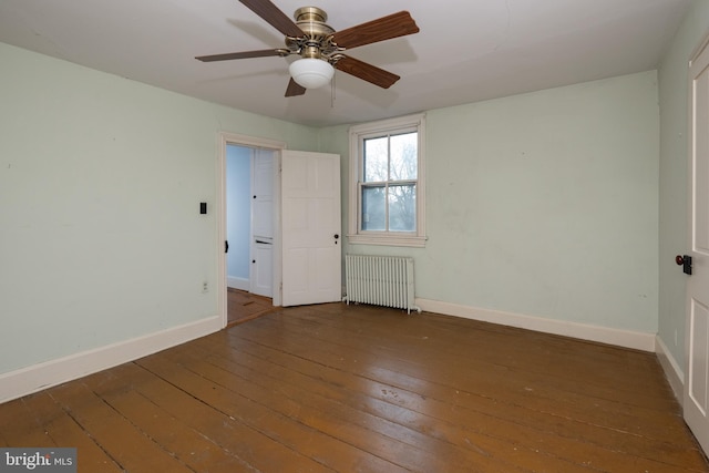 empty room featuring dark wood-type flooring, ceiling fan, and radiator heating unit