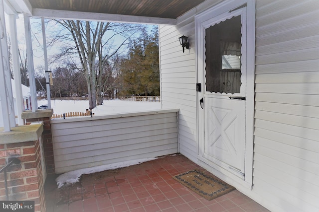 snow covered property entrance with covered porch