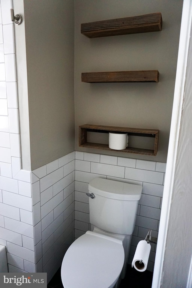 bathroom with toilet and tile walls