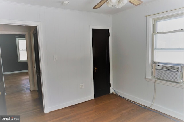 empty room featuring cooling unit, crown molding, ceiling fan, and dark wood-type flooring