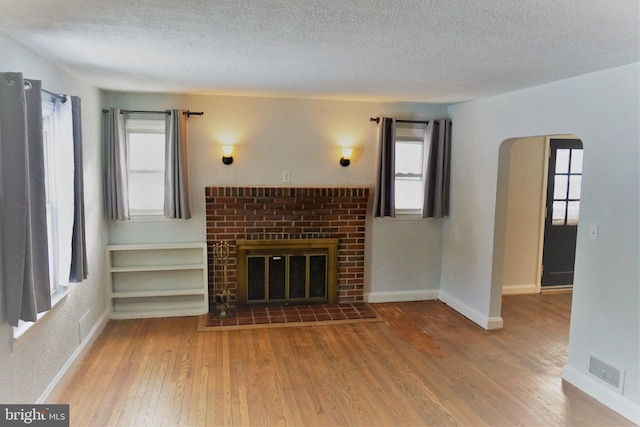 unfurnished living room featuring a fireplace, a textured ceiling, and hardwood / wood-style flooring