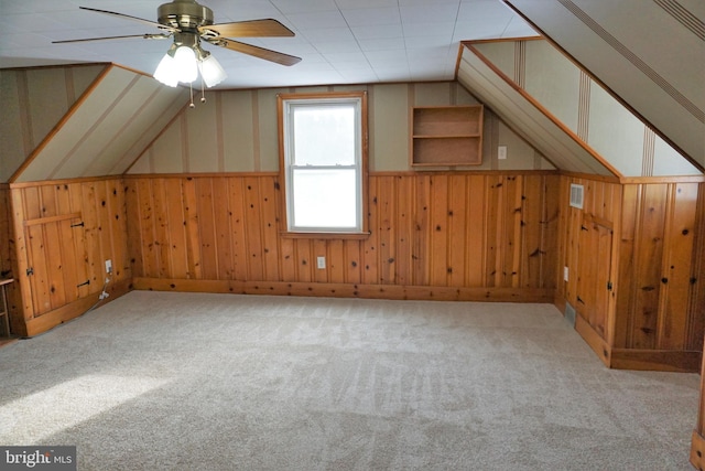 bonus room featuring ceiling fan, wooden walls, light colored carpet, and lofted ceiling