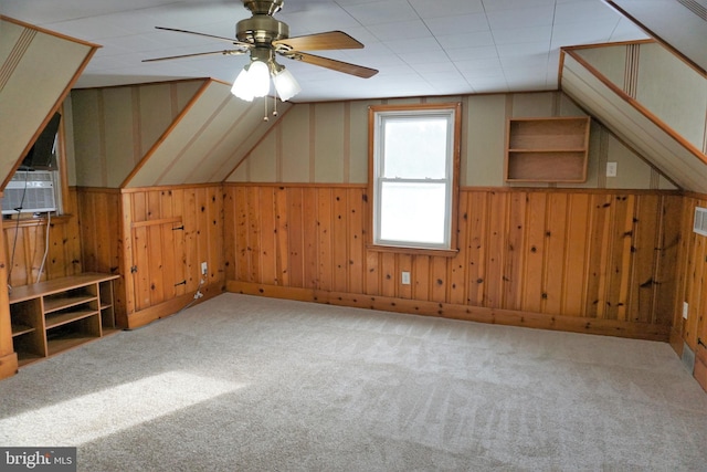 additional living space featuring carpet, vaulted ceiling, ceiling fan, and wood walls