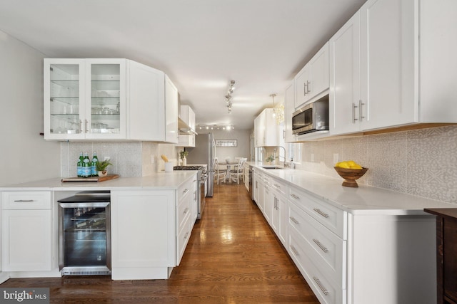 kitchen with white cabinetry, dark hardwood / wood-style flooring, beverage cooler, and appliances with stainless steel finishes