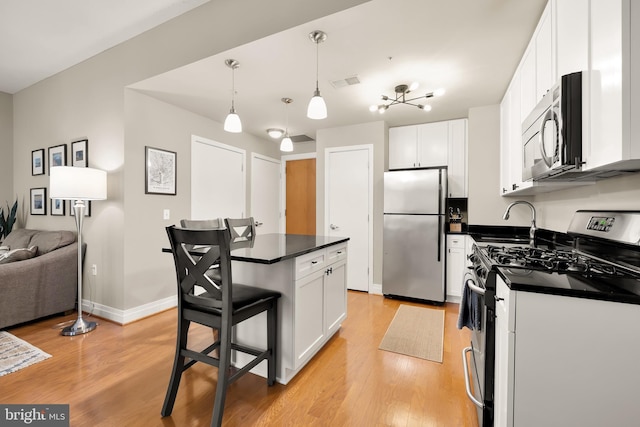 kitchen with pendant lighting, a breakfast bar, white cabinets, light hardwood / wood-style flooring, and stainless steel appliances