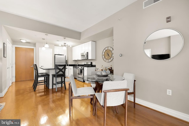 dining space featuring light hardwood / wood-style flooring and a chandelier