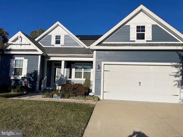 view of front of property with covered porch, solar panels, a garage, and a front lawn