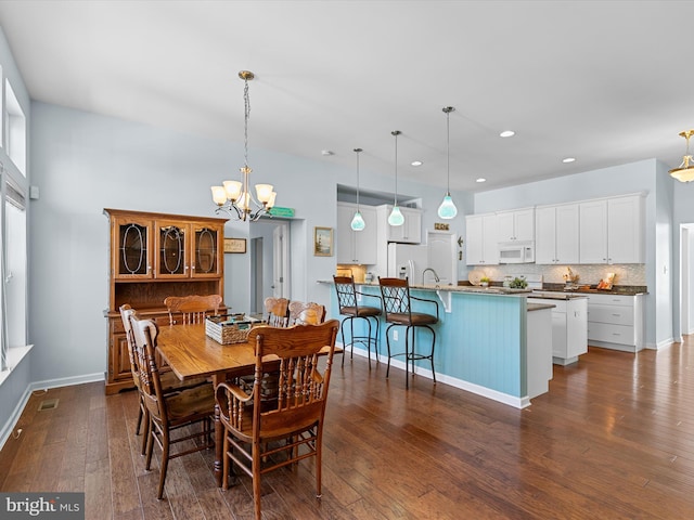 dining room with sink, dark hardwood / wood-style floors, and an inviting chandelier