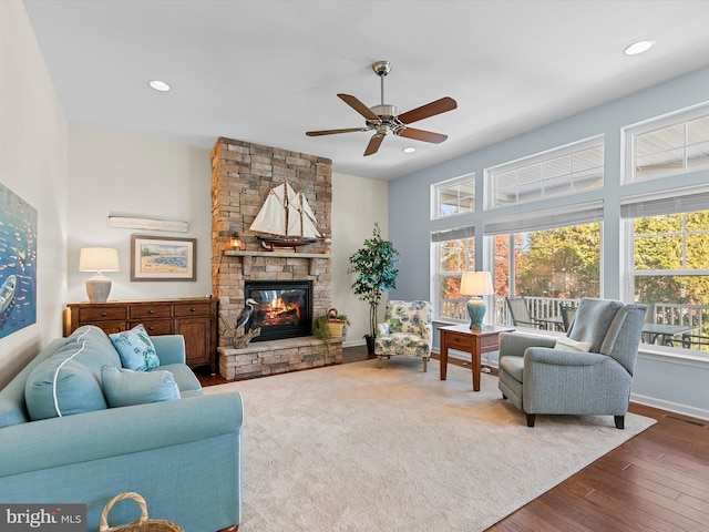 living room featuring hardwood / wood-style flooring, ceiling fan, and a fireplace