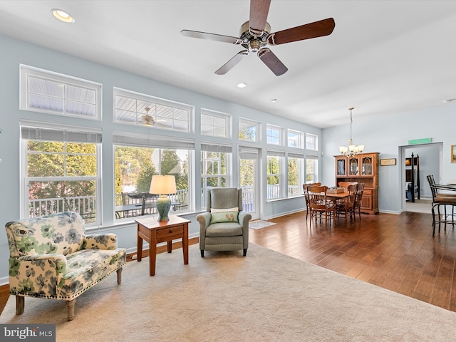 sunroom / solarium featuring ceiling fan with notable chandelier