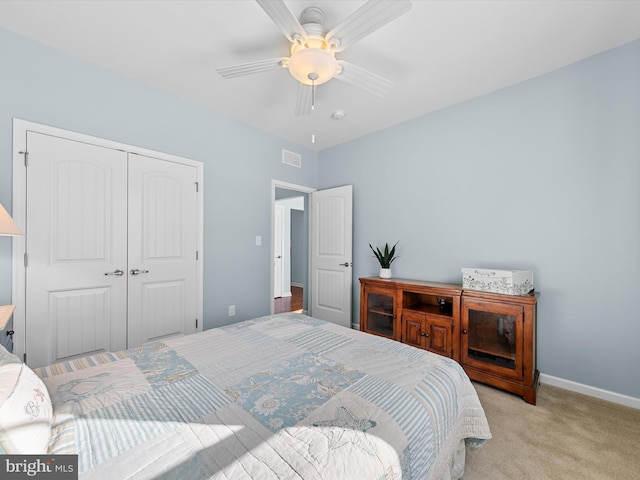 bedroom with ceiling fan, light carpet, and a closet