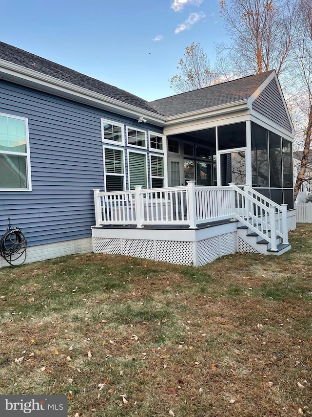 back of property featuring a sunroom, a yard, and a deck