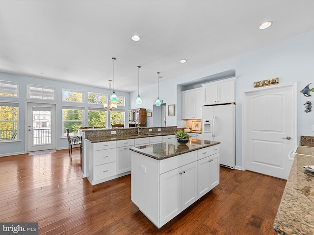 kitchen with pendant lighting, white cabinetry, a kitchen island, and white appliances