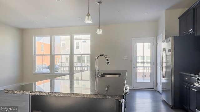 kitchen featuring sink, a wealth of natural light, stone countertops, and pendant lighting