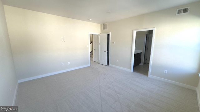 unfurnished bedroom with ensuite bath and light colored carpet