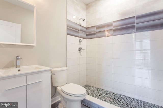 bathroom featuring tiled shower, vanity, and toilet