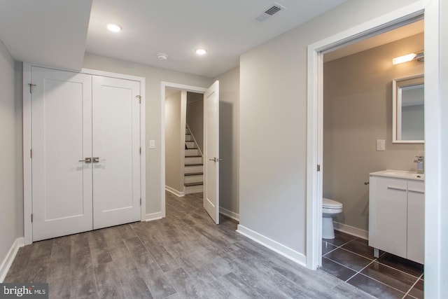 unfurnished bedroom featuring connected bathroom, a closet, dark wood-type flooring, and sink