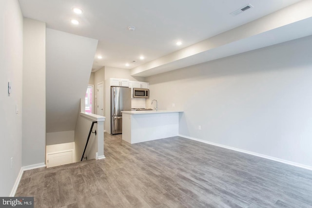 kitchen featuring white cabinetry, sink, stainless steel appliances, kitchen peninsula, and light wood-type flooring