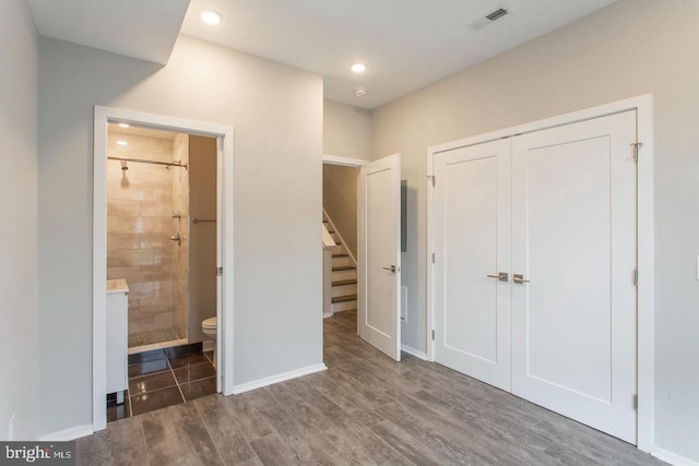 unfurnished bedroom featuring ensuite bath, a closet, and dark hardwood / wood-style flooring