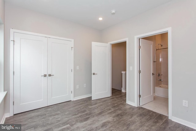 unfurnished bedroom with connected bathroom, a closet, and light hardwood / wood-style floors