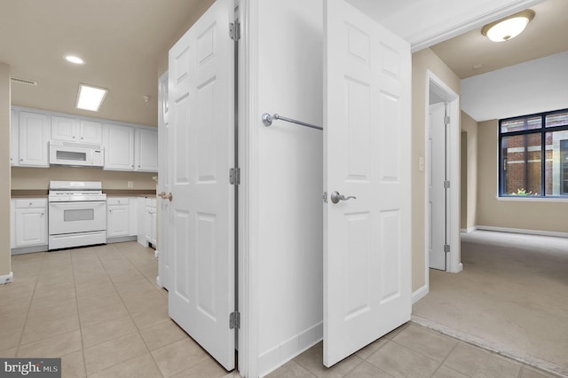 kitchen featuring light carpet, white cabinets, and white appliances