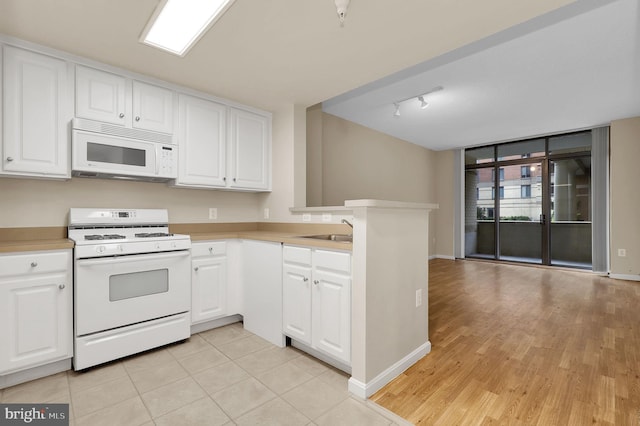 kitchen featuring sink, kitchen peninsula, track lighting, white appliances, and white cabinets