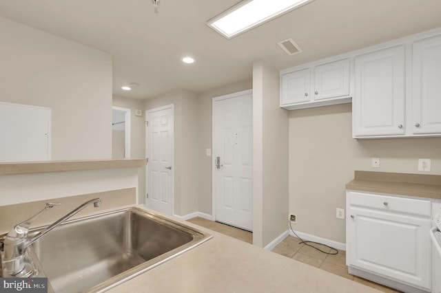 kitchen with white cabinets, light tile patterned floors, and sink