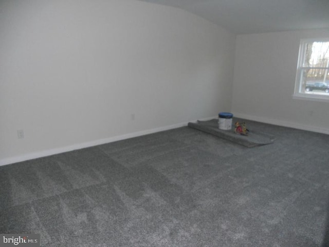 spare room with lofted ceiling and dark colored carpet