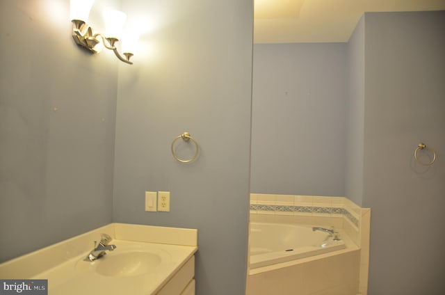 bathroom featuring tiled tub and vanity