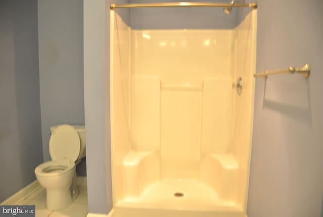 bathroom featuring a shower, tile patterned floors, and toilet